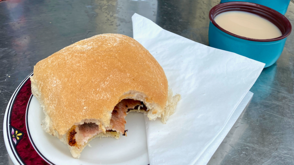Bacon roll and a cup of tea sitting on a cafe table
